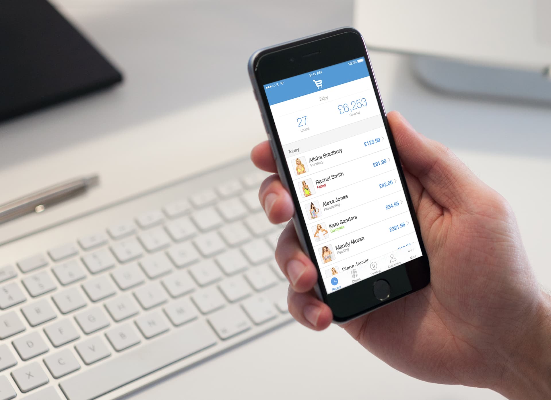 Hand holding an iPhone running the EKM orders app, showing daily revenue and recent orders
